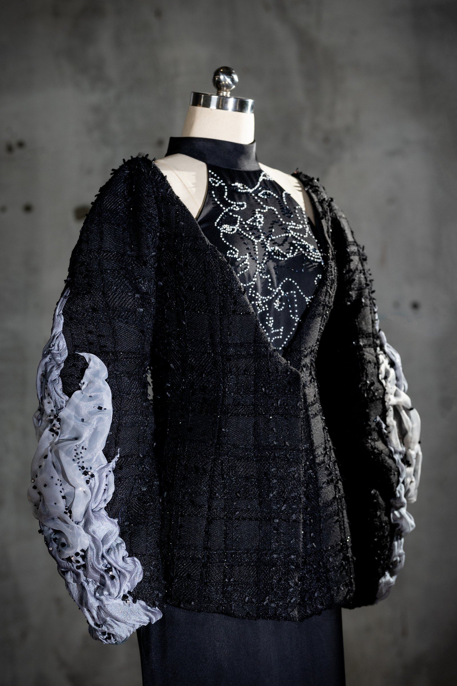 The Inner Faces jacket, front — stitched face line art at the chest with layered sleeves