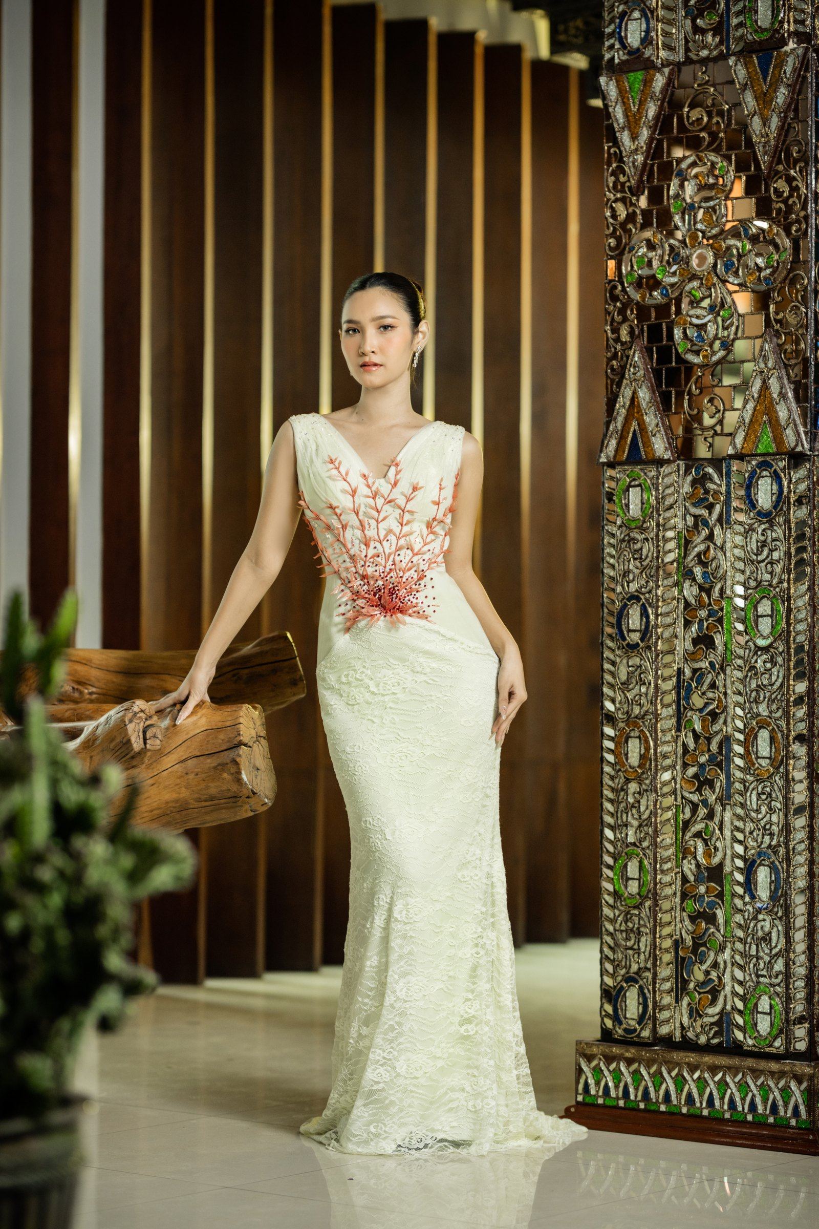 A cream lace gown with coral thread-work and beading worked across the bodice